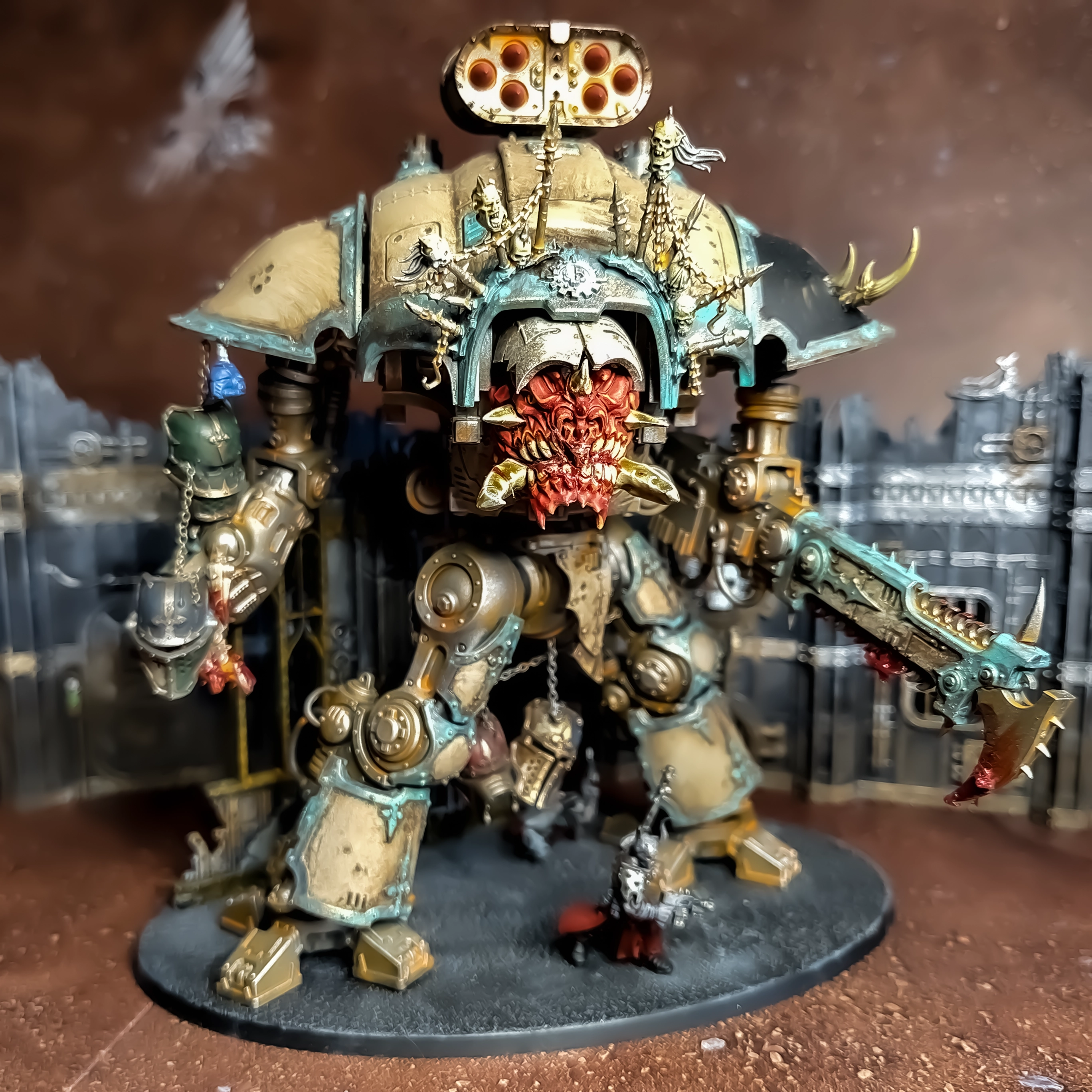 A photograph of a Chaos Knight model with a demonic face, some trophies and some blood and oxidation effects painted to a simple tabletop standard..